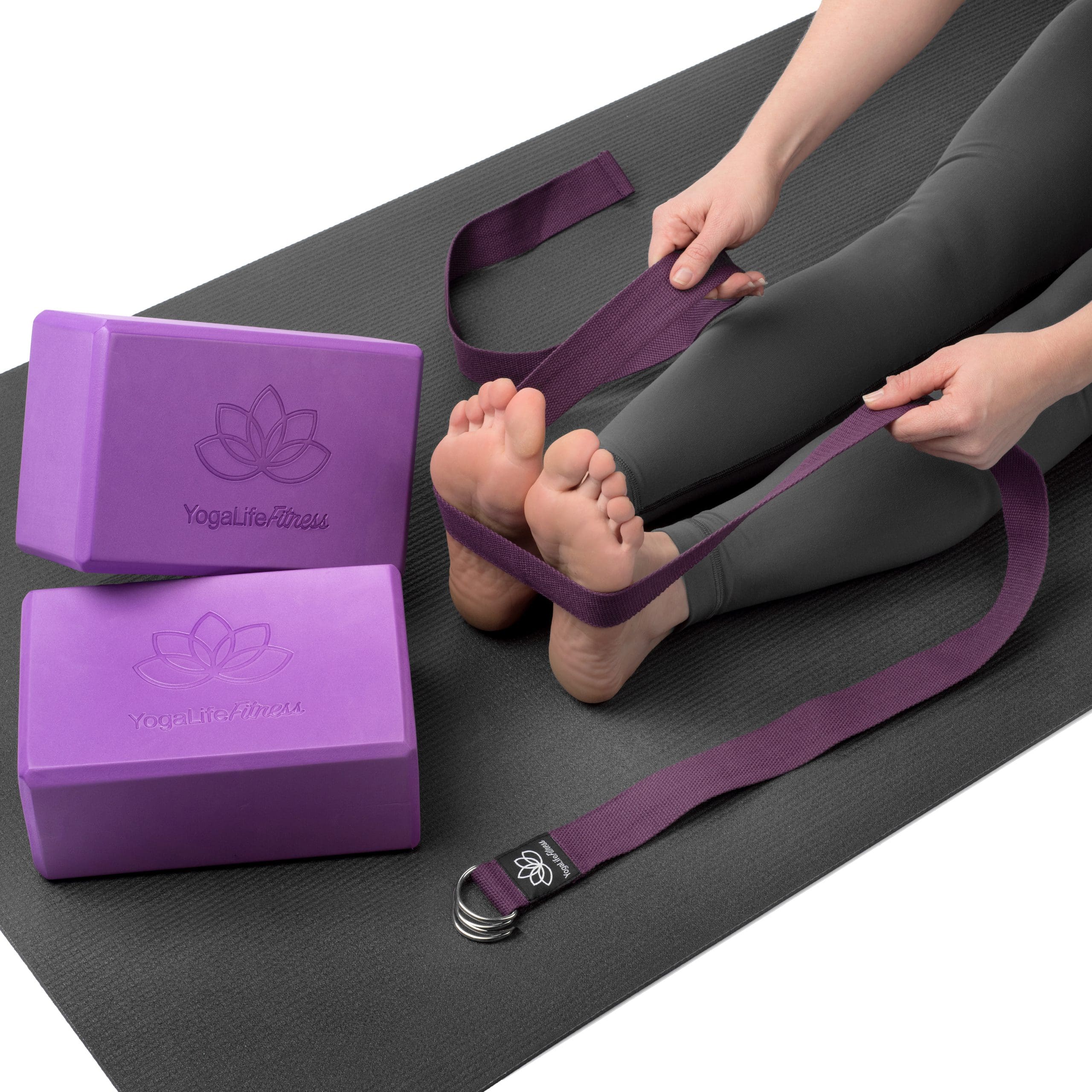 A foot model on a yoga mat with purple foam blocks and a purple strap.