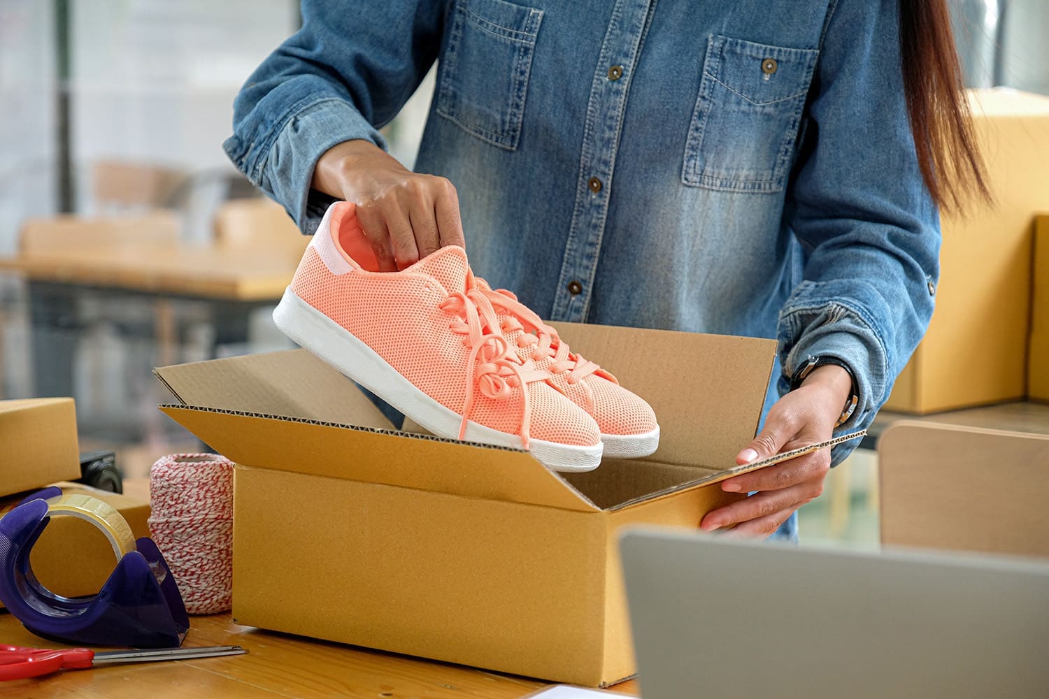 Woman packing shoes into a cardboard box for shipping to our studio.